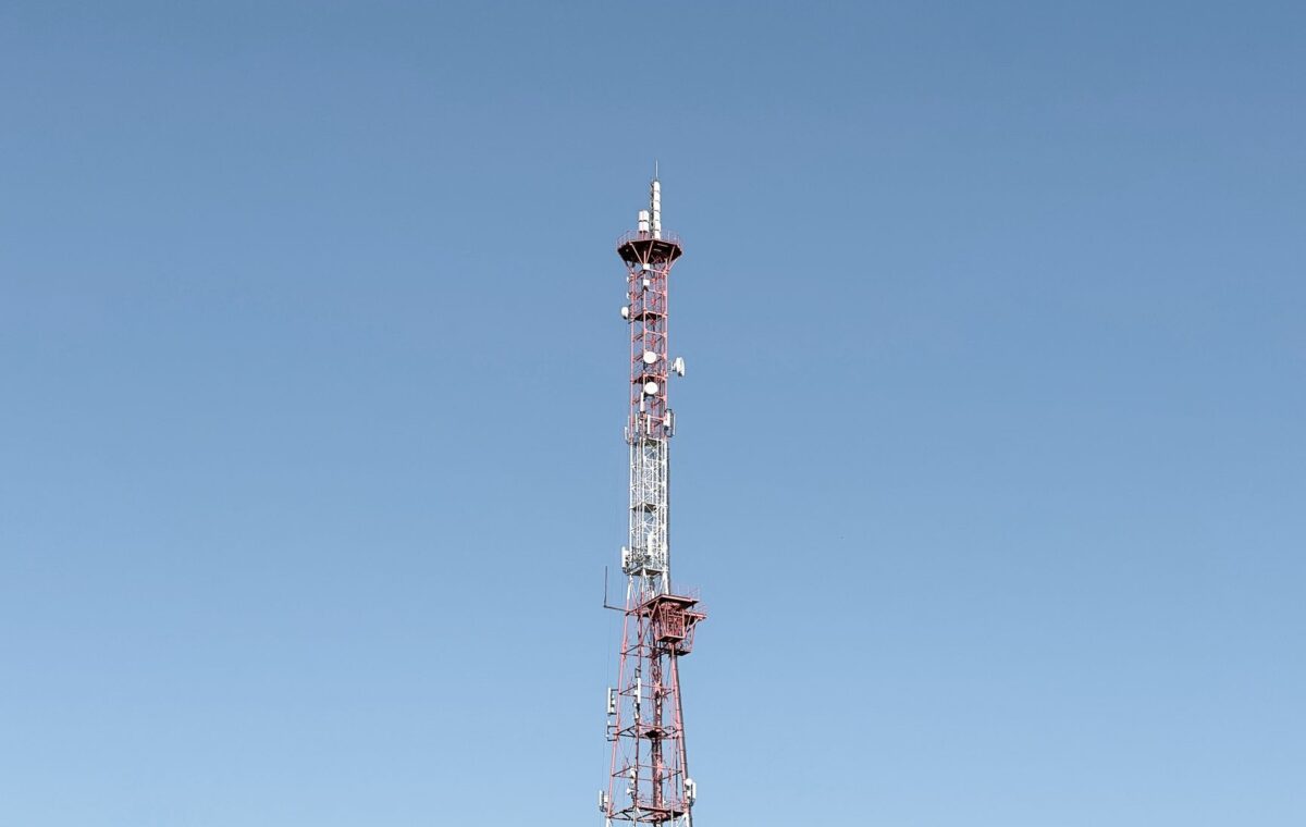 A tall communication tower set against a cloudless blue sky, symbolizing modern telecommunications.